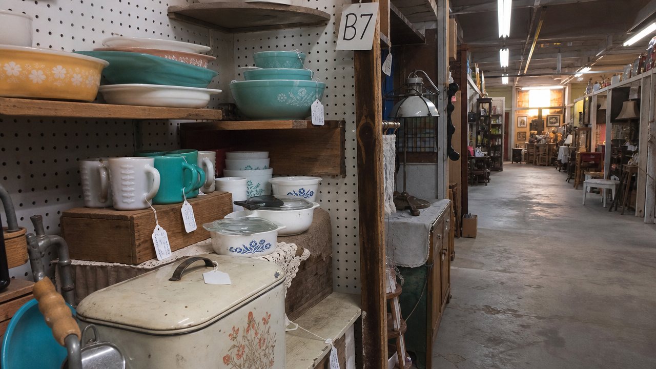Quiet antique mall aisle with a vintage kitchenware booth during a slow sales week